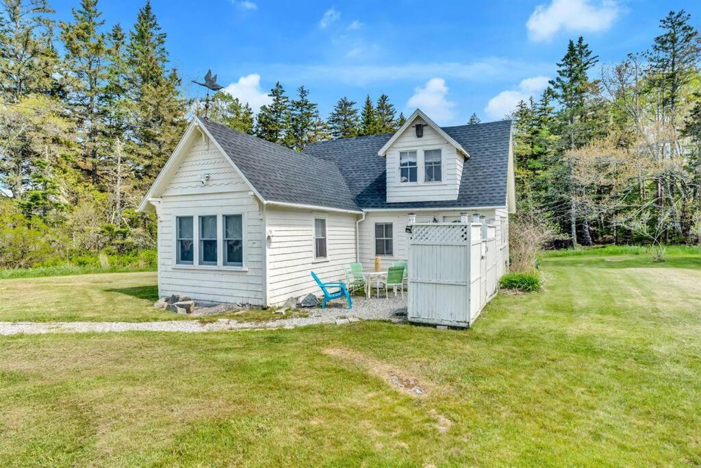 una pequeña casa blanca con patio en Quaint Maine Coast Cottage, en Saint George