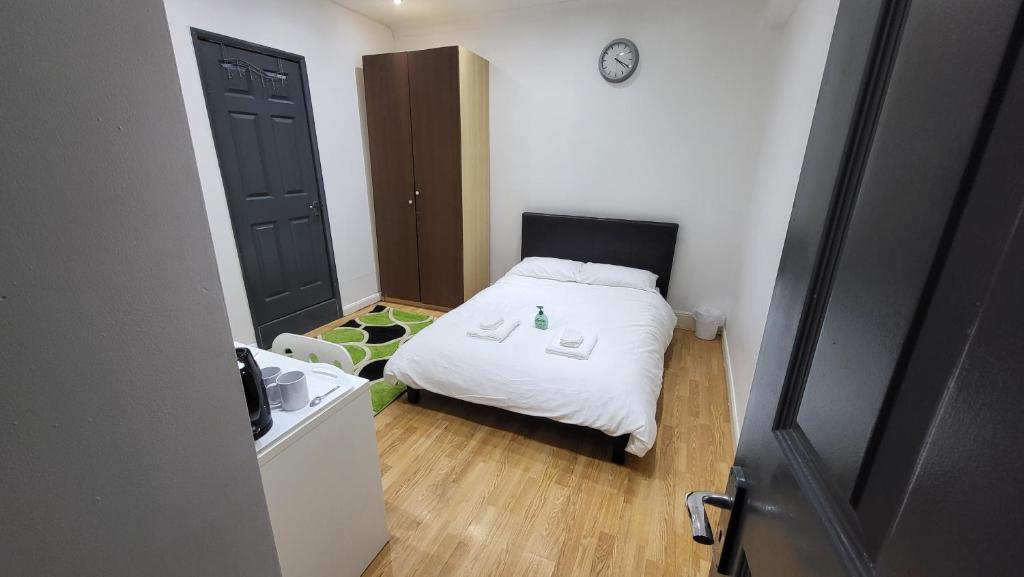 Habitación pequeña con cama blanca y puerta negra en Oleon en-suite Rooms - Ilford, London, en Ilford