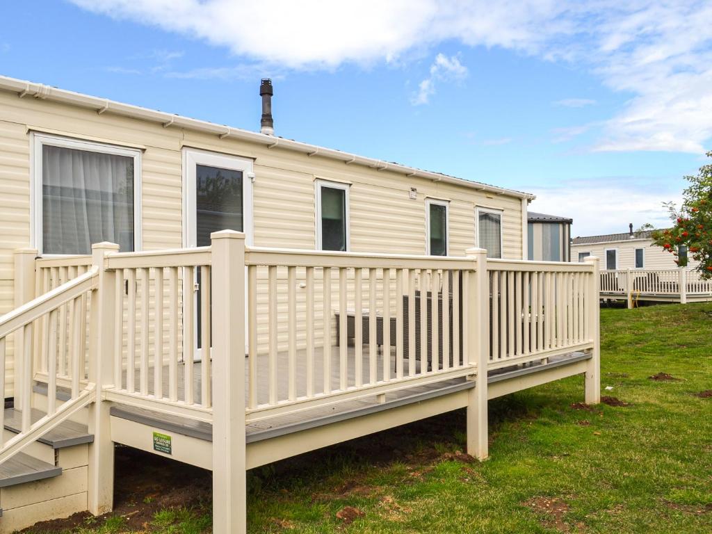 a white mobile home with a wooden deck at Summer Willow Lodge in Tattershall
