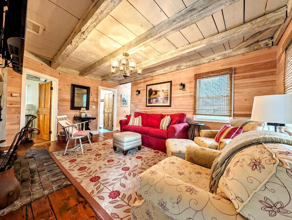 a living room with a red couch and a table at Oceanside Saltwater Cottage NEW in Milbridge