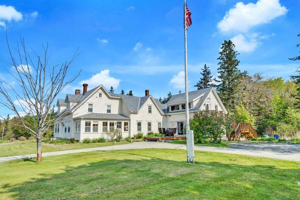 une grande maison blanche avec drapeau dans la cour dans l'établissement Seaside Serenity Farmhouse, à Saint George