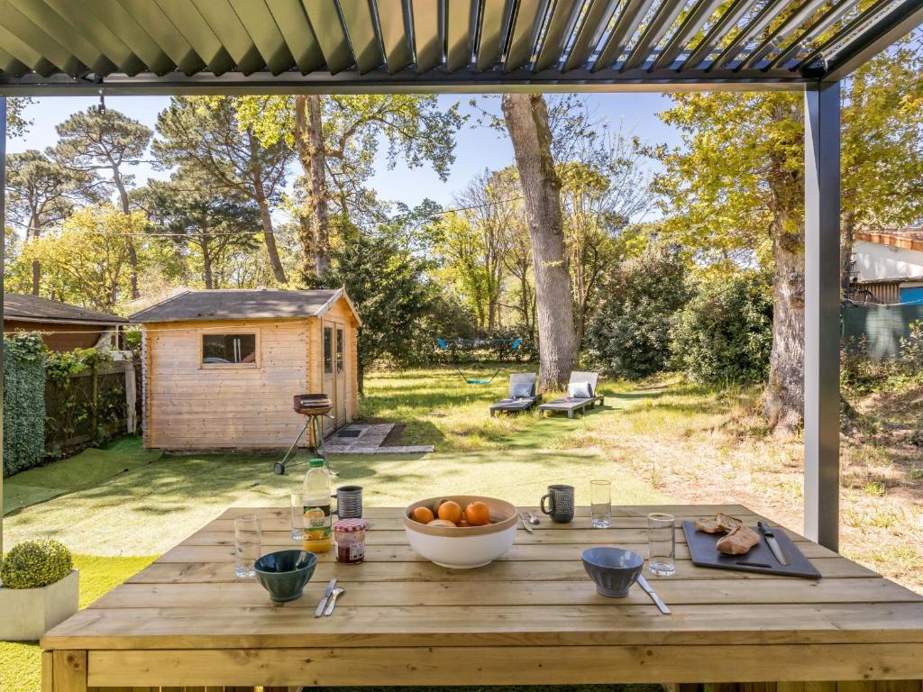 a wooden table with a bowl of oranges on it at Maison rénovée 2023 à 300m de la mer avec terrasse, jardin clos, clim et wifi - FR-1-306-1270 in Saint-Brevin-les-Pins