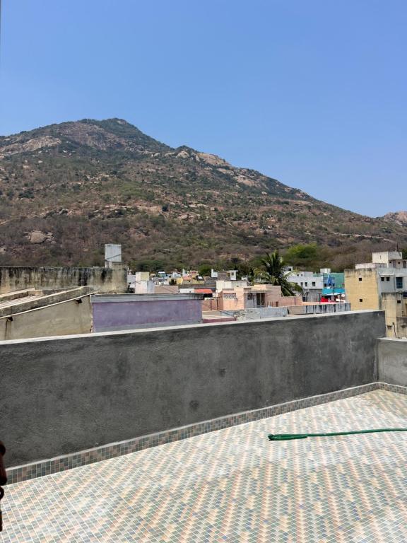 uma pessoa de pé sobre um telhado com uma montanha ao fundo em Duplex Room Stay at Hill View em Tiruvannamalai