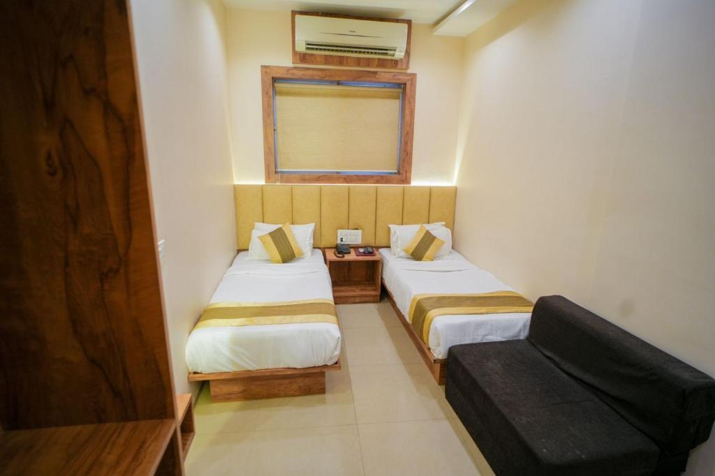 Hotel Skylink Hospitality Next to Amber Imperial في مومباي: غرفة صغيرة بها سريرين وأريكة