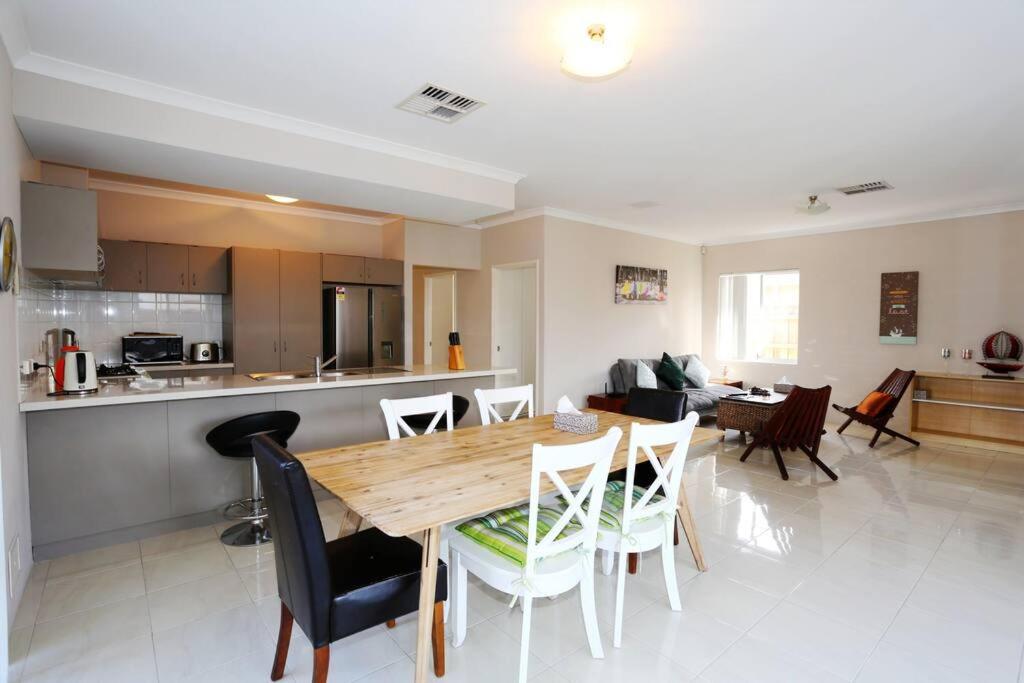 a kitchen and living room with a wooden table and chairs at Nice and Neat House for your Journey - Renovated in Perth