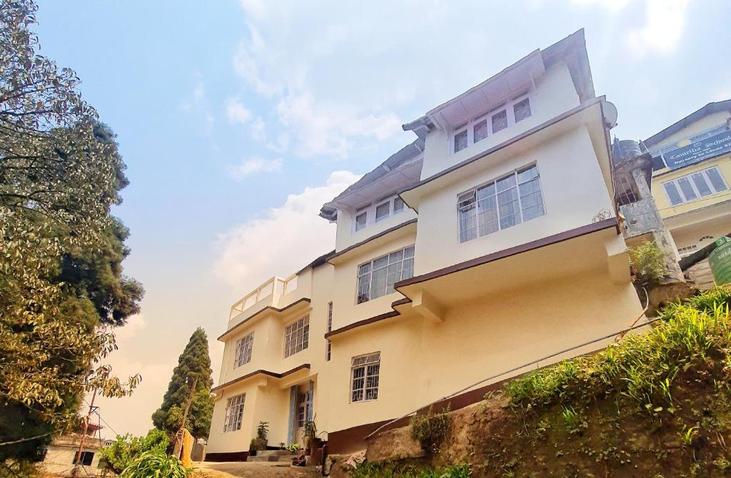 a large yellow and white building with trees at Shree Niwas in Darjeeling