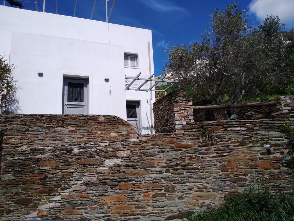 a stone wall in front of a white building at Ανδρος Αρκουδα in Andros