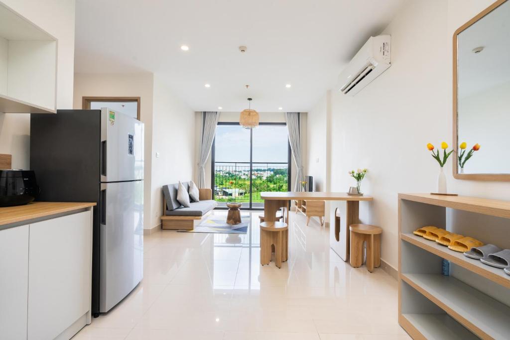 a kitchen with a refrigerator and a living room at Emma House 4 - Can ho 2PN Vinhomes Grand Park Quan 9 in Gò Công