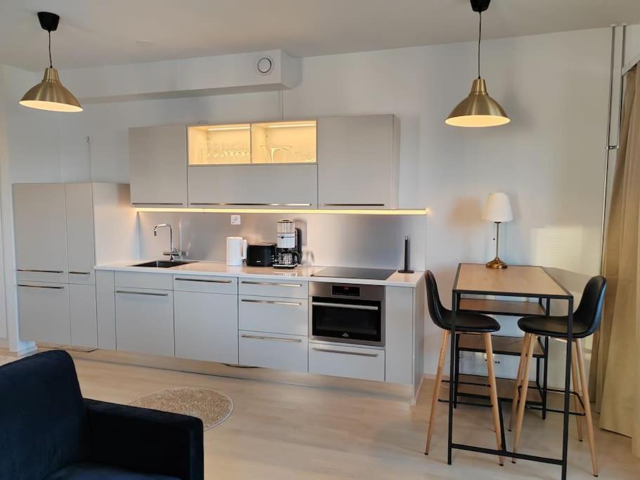 a kitchen with white cabinets and a table and chairs at Keskustan tyylikkäin studio in Lappeenranta