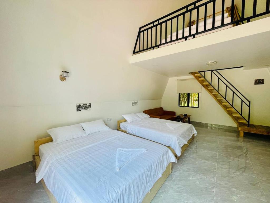 two beds in a white room with a staircase at HOLY VILLA A Frame 3beds 1sofa bed 1bathroom in Kampot