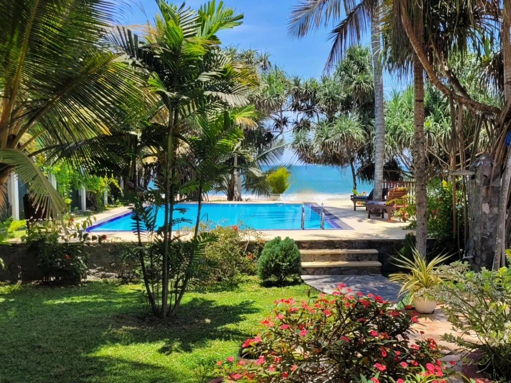 een zwembad met palmbomen en een strand bij Czech House in Tangalle