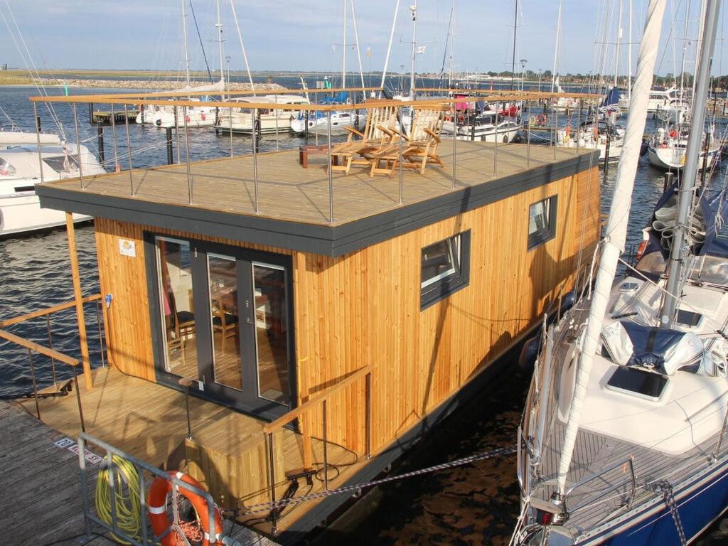 a wooden boat with tables and chairs on the deck at Premium houseboat on the lake in Heiligenhafen