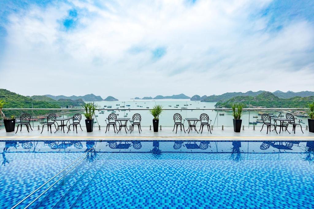 een zwembad met stoelen en uitzicht op het water bij Cat Ba Paradise Hotel- Pool & Sky Bar in Cat Ba