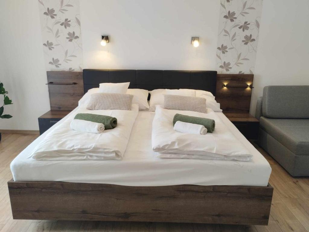a large bed with white sheets and green pillows at Krisztina Vendégház in Zalaszentlászló