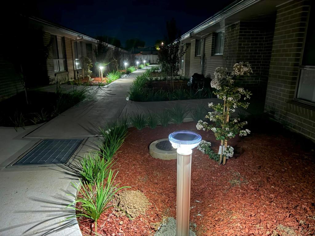 a light in a yard next to a house at night at French Corner Apartments in Dubbo