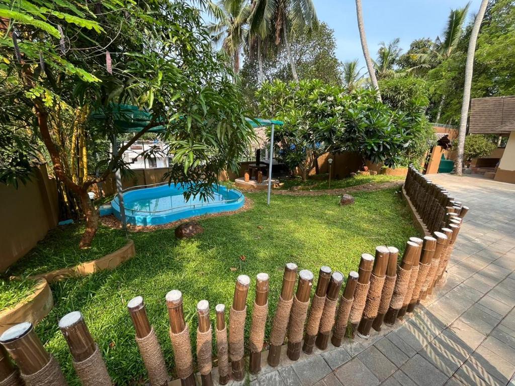 a fence in front of a yard with a pool at Cocoon Earth Home - Pool Villa Kovalam in Kovalam