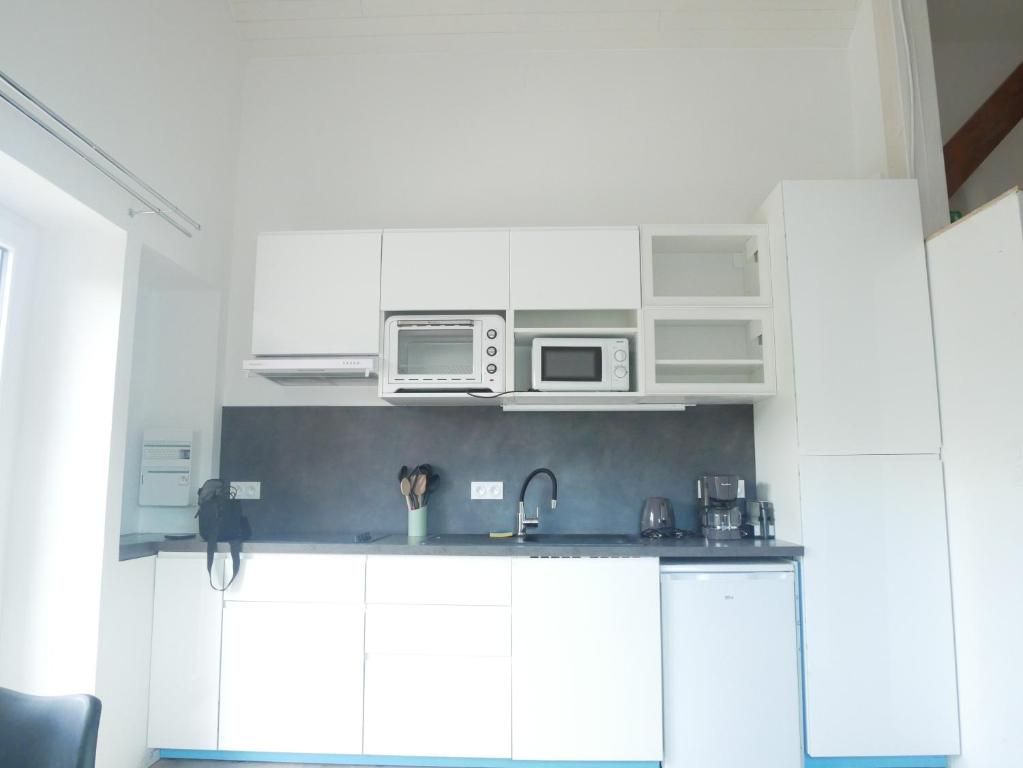 a kitchen with white cabinets and a sink and microwave at Villa Cathy Studio in Aix-les-Bains