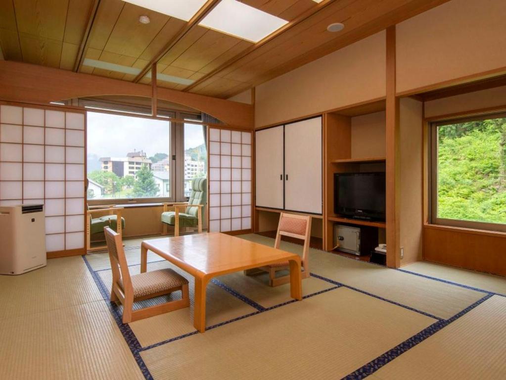 - un salon avec une table, des chaises et une télévision dans l'établissement KKR Yuzawa Yukiguni, à Yuzawa