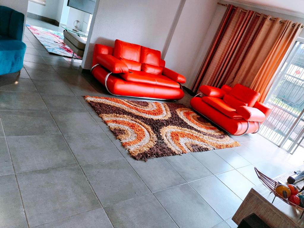 a living room with two red chairs and a rug at Reutlwane Gardens house in Secunda