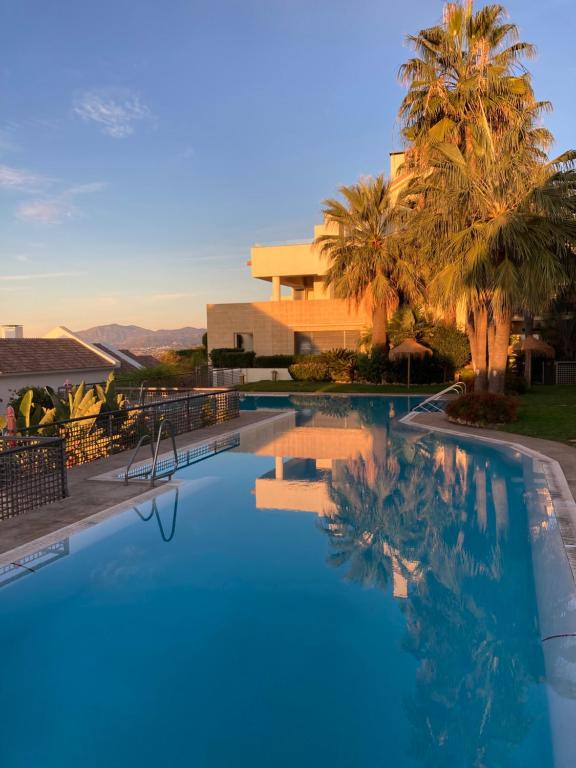 einem großen Pool mit Palmen und einem Gebäude in der Unterkunft Los Monteros Hill Club Marbella in Marbella