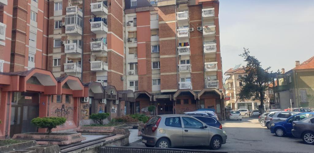 un estacionamiento con autos estacionados frente a un edificio en TOP Center Apartment, en Bitola