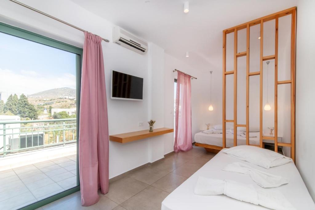 a bedroom with two beds and a large window at Ageri Hotel in Tinos