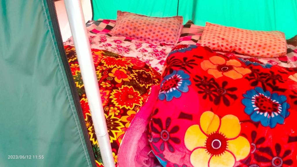 a bed with a colorful blanket and pillows on it at NamasteNomads X Musafirokibasti in Kedārnāth
