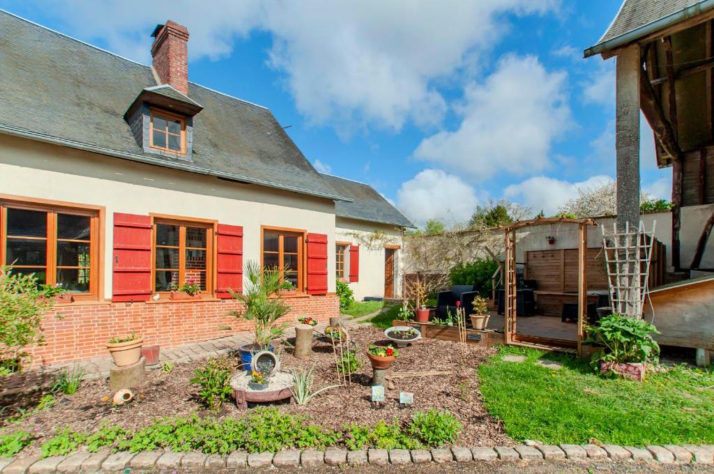 un jardín frente a una casa con persianas rojas en Aux Passiflores en Cempuis