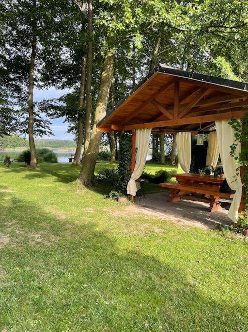 a picnic shelter with a bench in the grass at Leśny Zakątek in Chycina