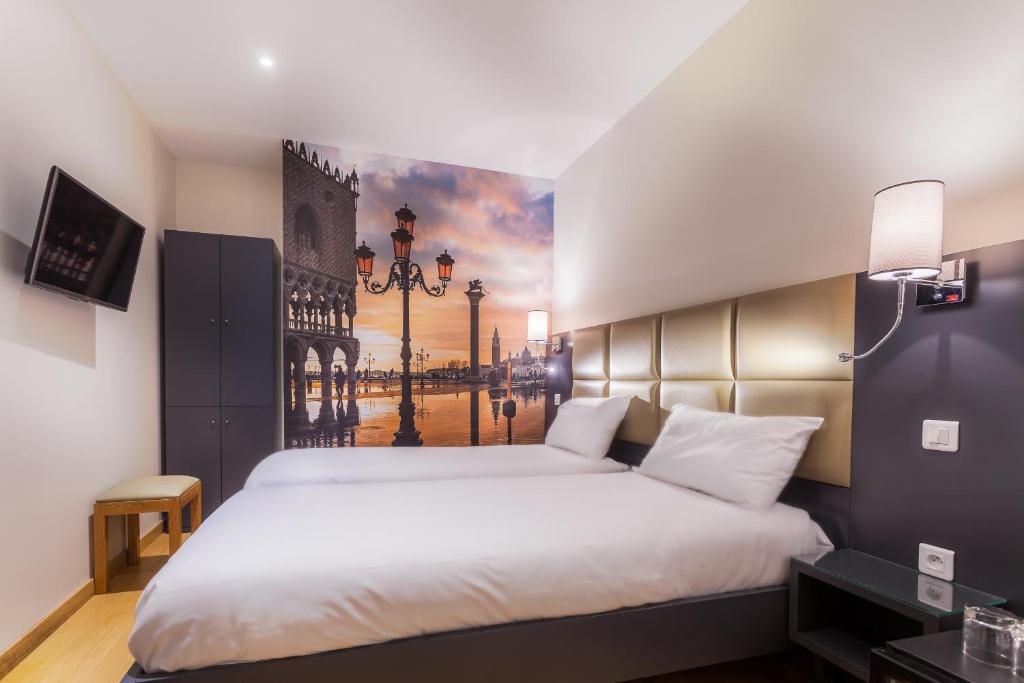 a bedroom with a large bed with a painting on the wall at Hotel Jenner in Paris