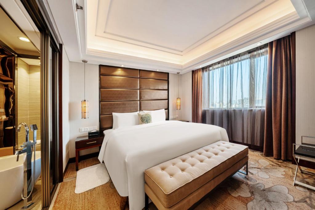 um quarto com uma grande cama branca e uma janela em GuangDong Hotel Shanghai em Xangai