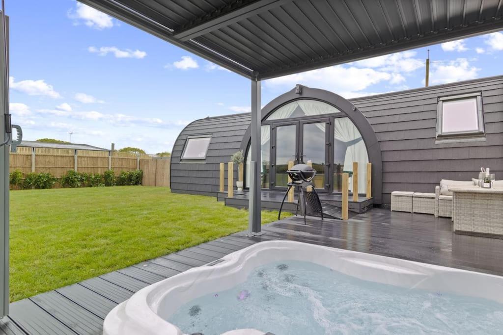 una bañera de hidromasaje en una terraza en un patio trasero en Choller Lodges - The Barn House With Hot Tub en Arundel