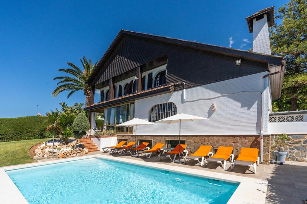 Villa mit einem Pool und orangefarbenen Stühlen in der Unterkunft Casa El Maizal in Marbella