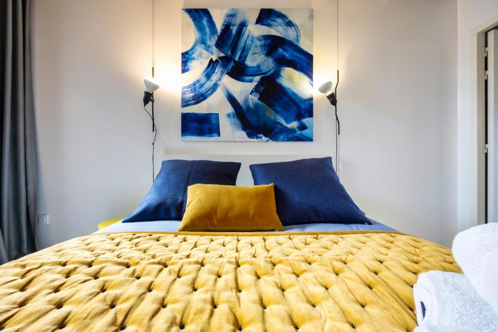 a bedroom with a bed with blue and yellow pillows at L'INOX in Toulouse
