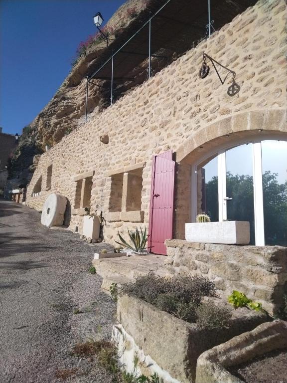 un bâtiment en briques avec une porte rose sur le côté dans l'établissement Studio troglodyte en Provence, à Cornillon-Confoux