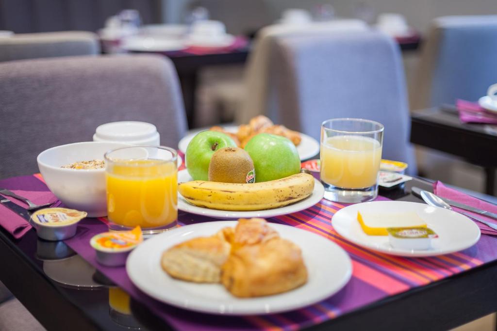 a table with plates of food and glasses of orange juice at Hotel Jenner in Paris