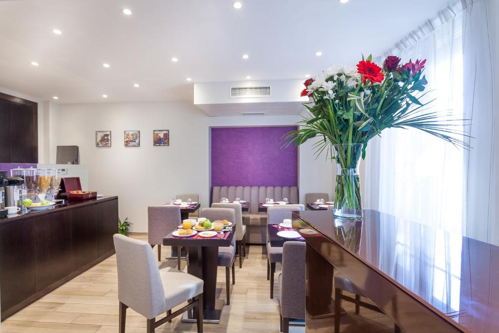 a dining room with a table with a vase of flowers at Hotel Jenner in Paris