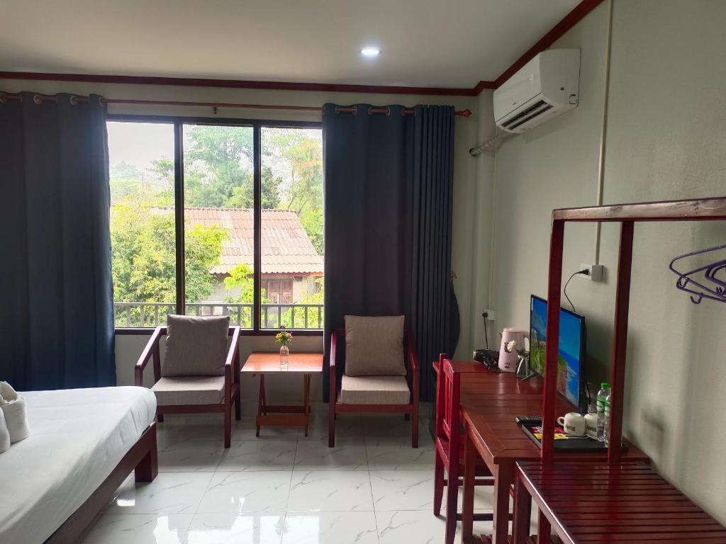 Vang Vieng Champa Hotel في فانغ فينغ: غرفة فندقية بسرير وطاولة وكراسي