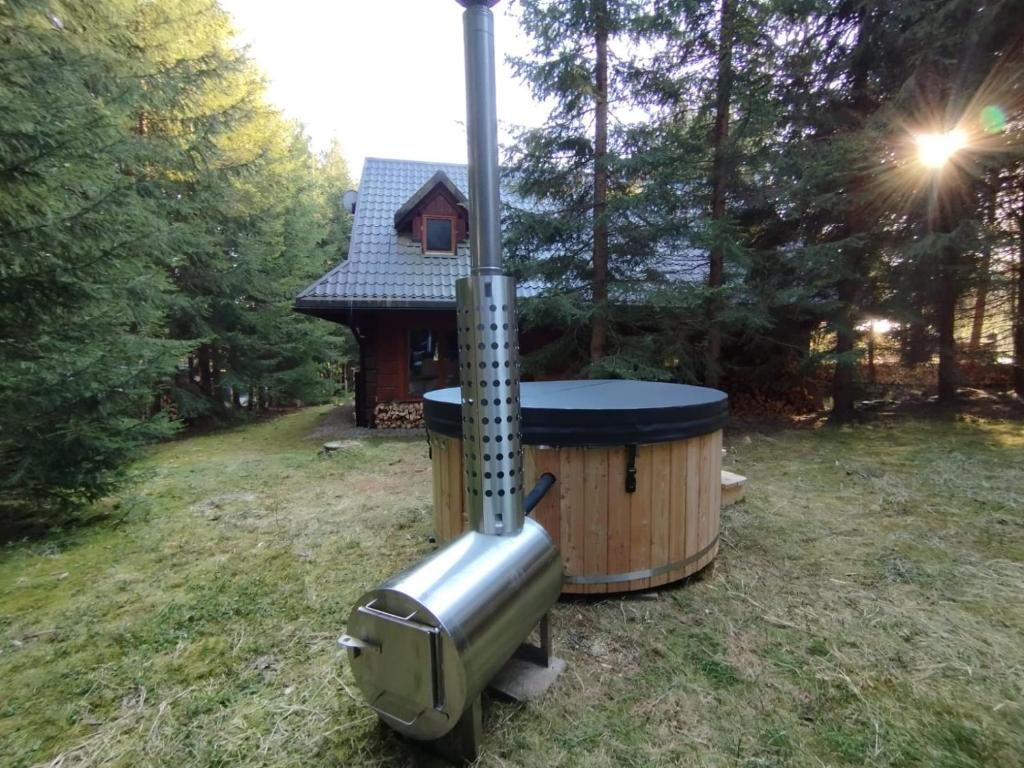 a hot tub in the grass next to a house at domek w zaczarowanym lesie in Istebna