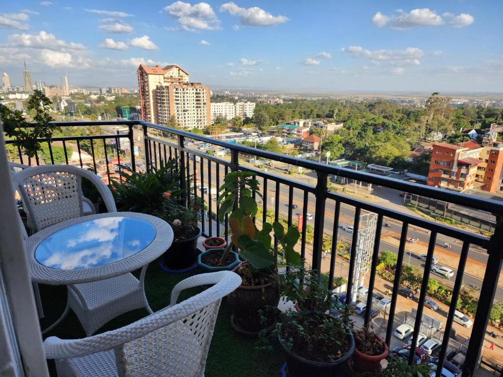 a balcony with a table and chairs and a view of a city at Vesta Garden Apartment in Nairobi