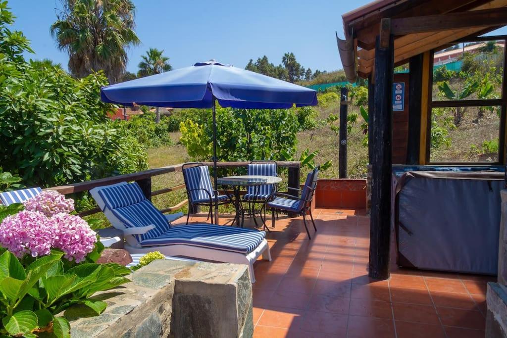 CASA RÚSTICA CON JACUZZI في لاس بالماس دي غران كاناريا: فناء مع كراسي وطاولة مع مظلة