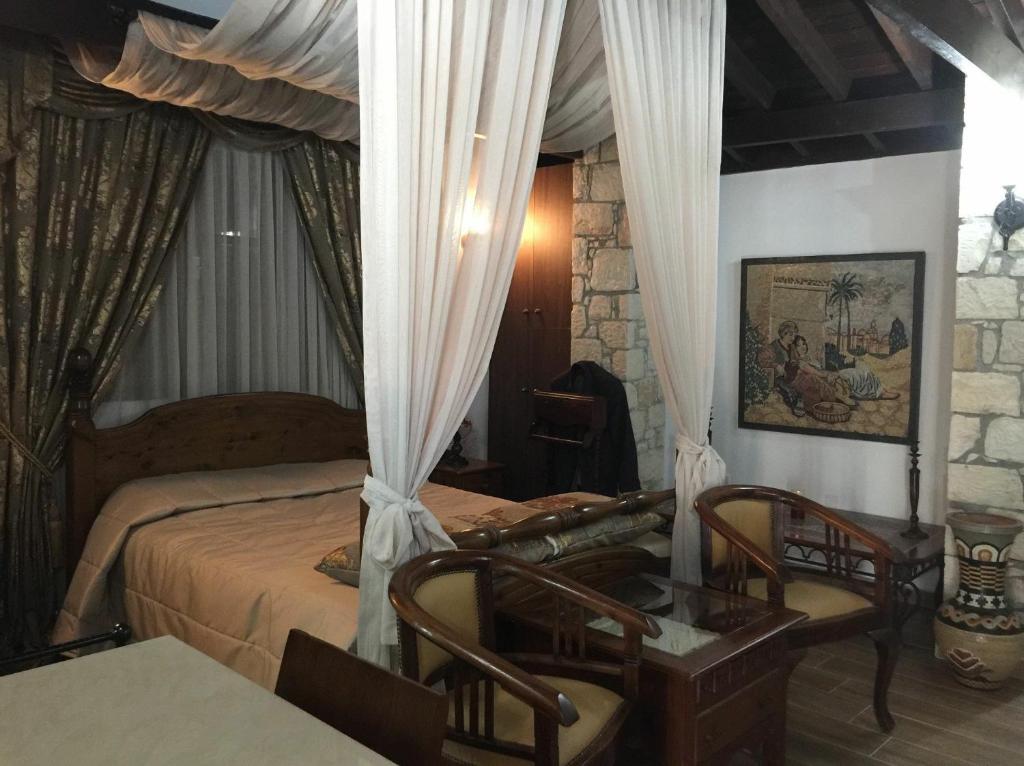 sypialnia z łóżkiem z zasłonami i stołem w obiekcie DEMICHANNA POOL HOUSE AND LUXURY SUITE WITH PRIVATE POOL w mieście Anarita