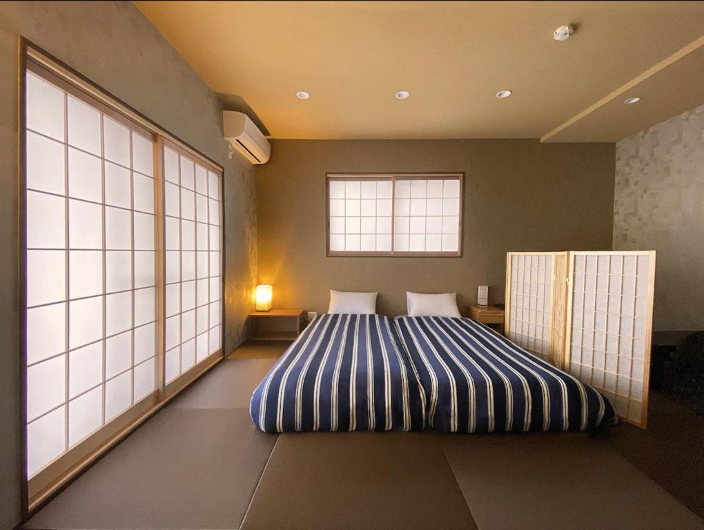 a bedroom with a bed in a room with a window at My Home Inn Izumisano in Izumi-Sano