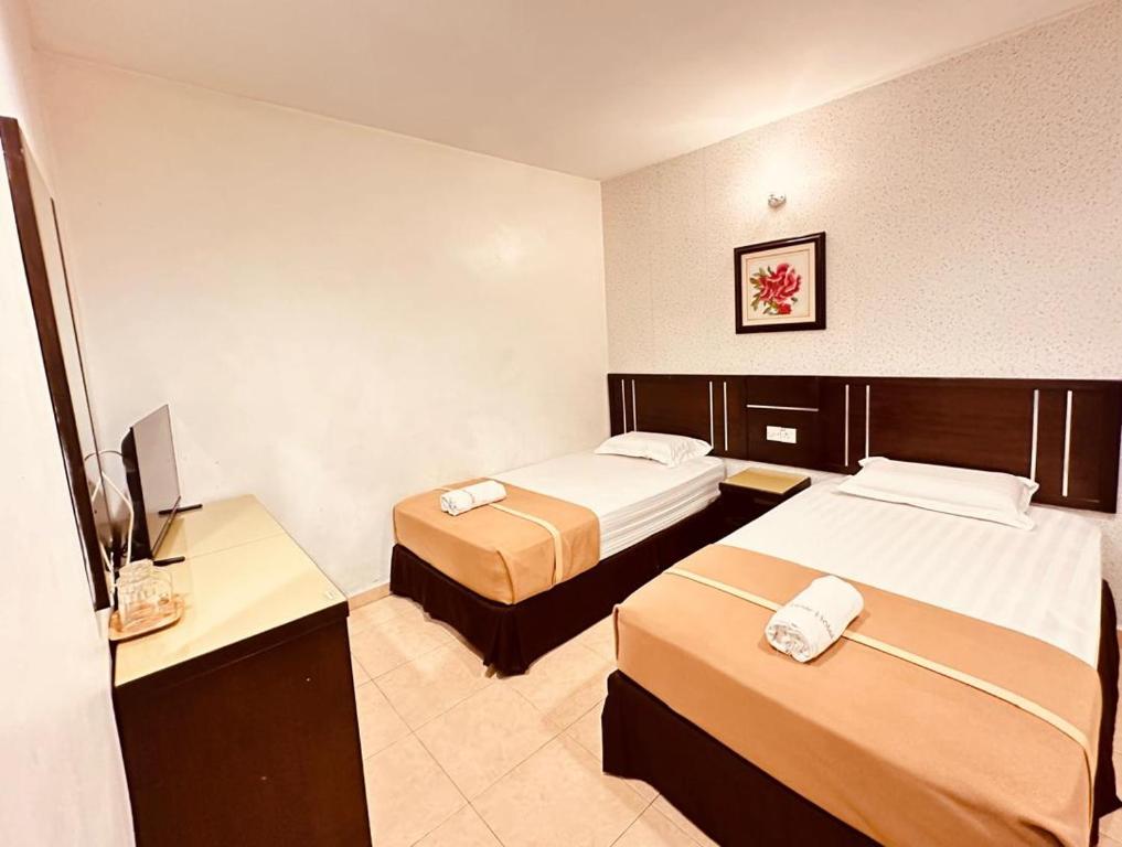 a hotel room with two beds and a television at Rainbow Hotel in Alor Setar