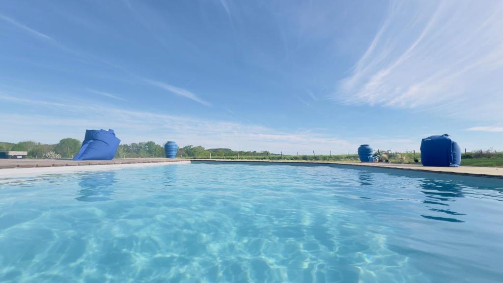 a swimming pool with blue chairs and a blue sky at La Demeure en Périgord in Anlhiac