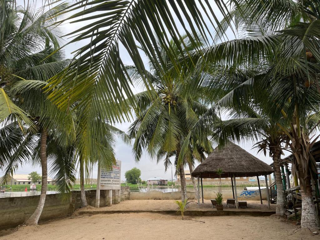 a group of palm trees with a gazebo at Hotel Germain - Ganvié Holiday Resort in Ganvié