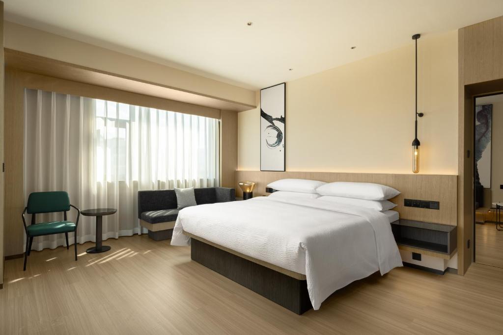 a bedroom with a large white bed and a chair at Fairfield by Marriott Lijiang Ancient Town in Lijiang