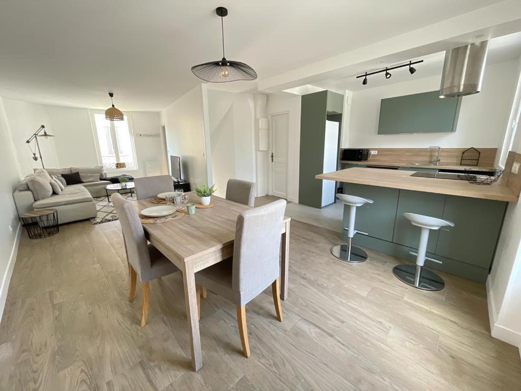 a kitchen and living room with a wooden table and chairs at La Grenouillère in Brie-Comte-Robert