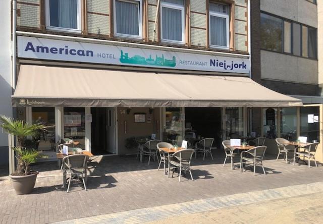 restauracja ze stołami i krzesłami przed budynkiem w obiekcie Hotel American w mieście Venlo