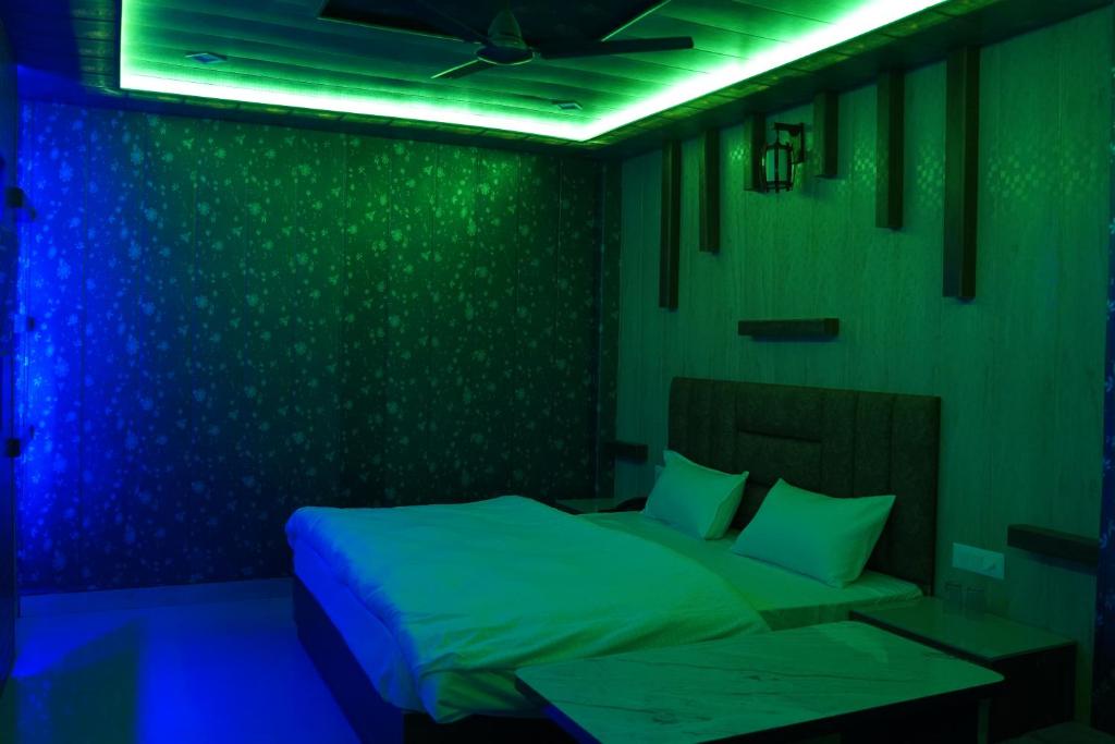 a green room with a bed with blue lights at JB Hotel and Resort in Lohaghāt